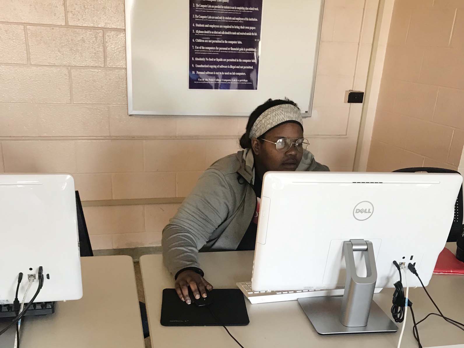Girl sits at desk working on a computer.