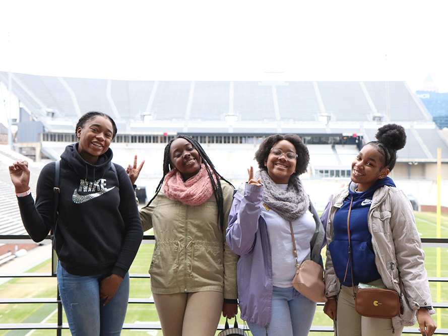 Girls pose on Georgia Tech football field.